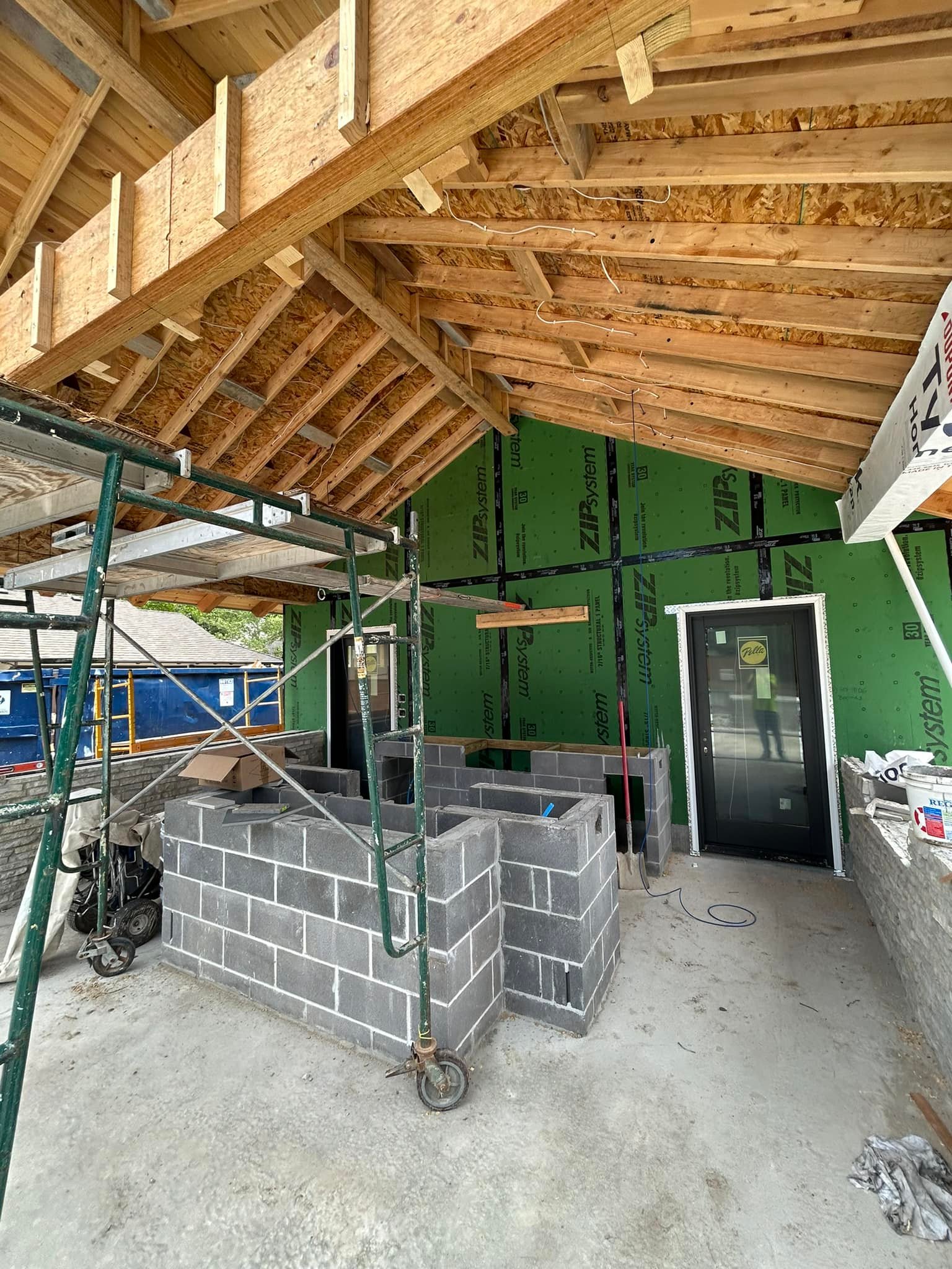 Kitchen under construction featuring a green wall, with an electrician working on electrical installations.